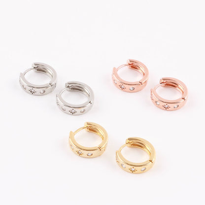 Flat lay of silver, rose gold, and gold huggie earrings with cubic star accents on white background.