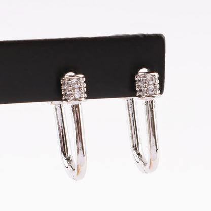 Silver pavé hoop earrings displayed on a black holder, showcasing the crystal cylinder clasp in detail.