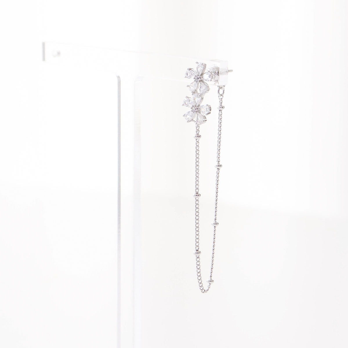 Single silver floral crystal ear jacket with chain displayed on white