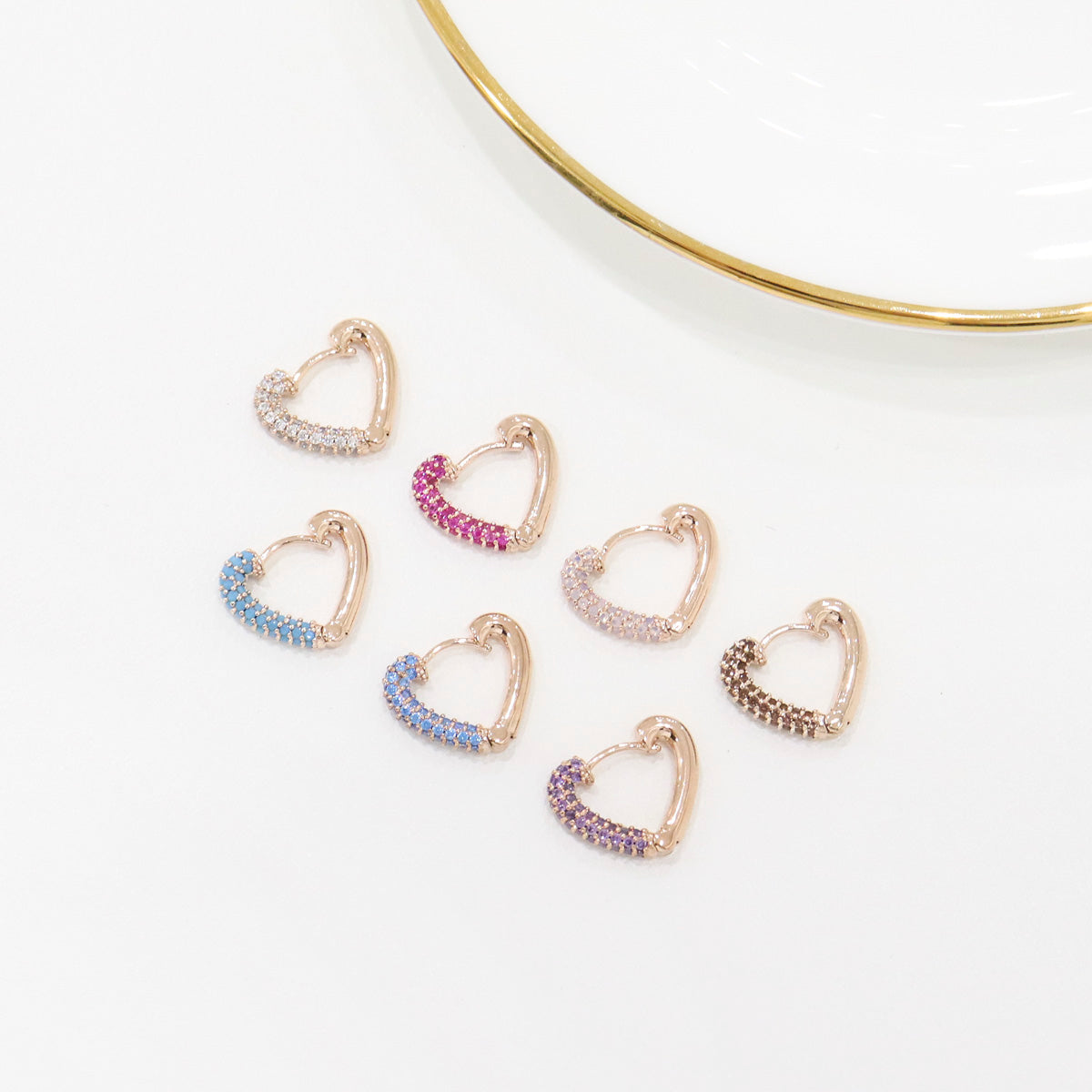 Set of heart-shaped earrings with colorful stones on a white background