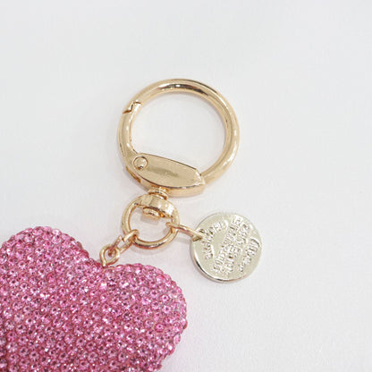 Close-up of the pink keychain’s hardware.
Focus on the gold ring and engraved medallion detail.