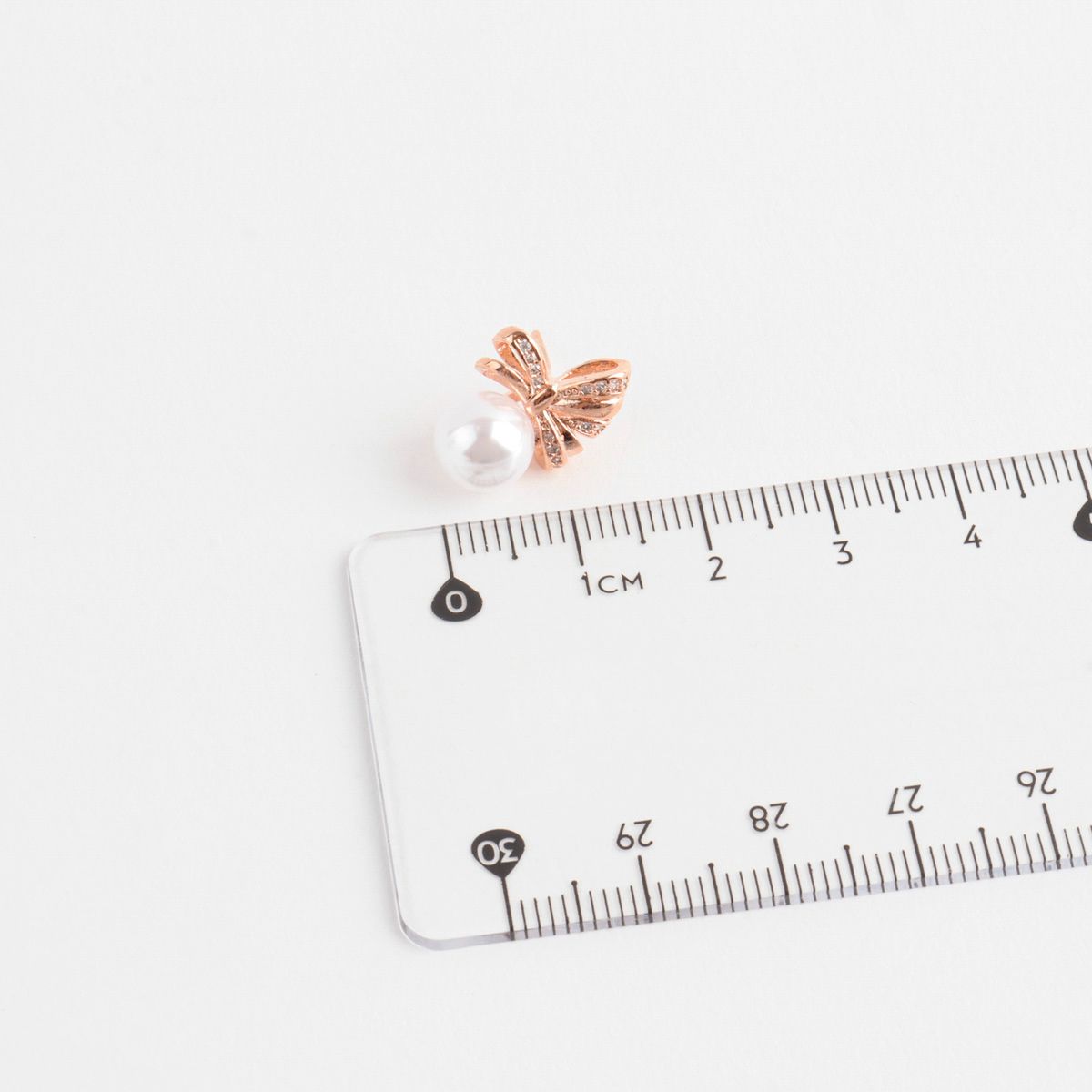 Pearl bow earring size measurement with ruler showing 1.5cm height