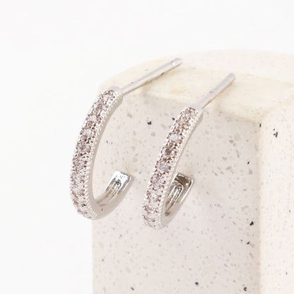 Zoomed view of silver cubic zirconia mini hoops placed upright on a speckled stone block.