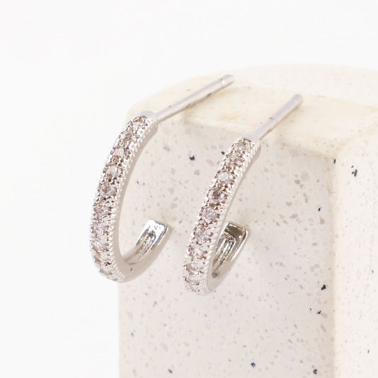 Zoomed view of silver cubic zirconia mini hoops placed upright on a speckled stone block.
