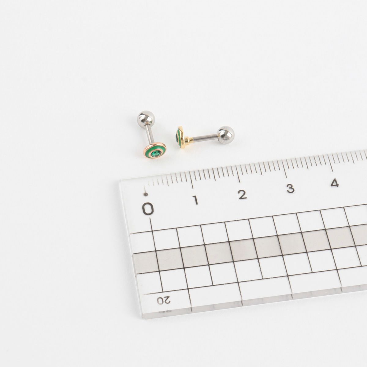 Size comparison of green epoxy barbell earring next to a ruler