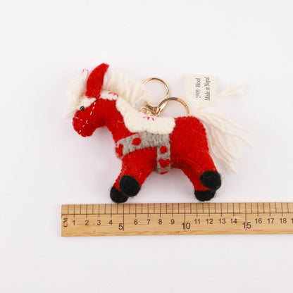 Red horse felt keychain measured with ruler showing 10-11 cm size, handmade wool texture visible