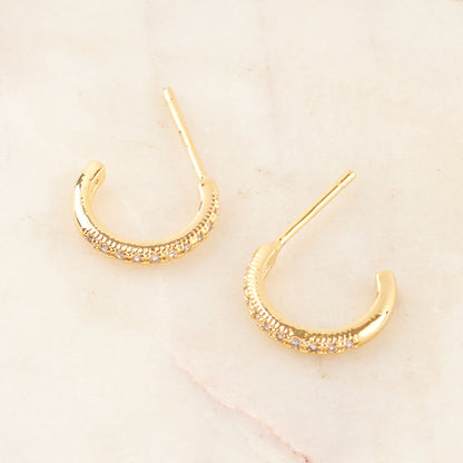 Gold mini hoop earrings with cubic zirconia lined on the front, placed on a warm marble surface.

Image 6
