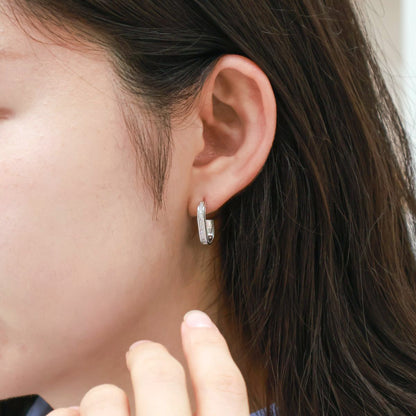 Silver oval drop stud earrings worn on ear - side view