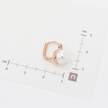 One pink-stone pearl drop earring laid on a measurement grid in centimeters for size reference.