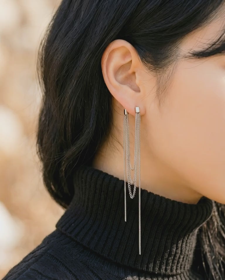 Woman wearing gold front and back chain earrings with black turtleneck showing elegant drape