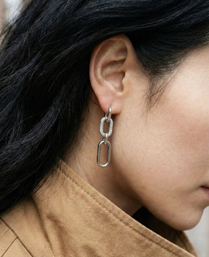 Side profile of woman wearing gold chunky drop earrings, elegant urban street style