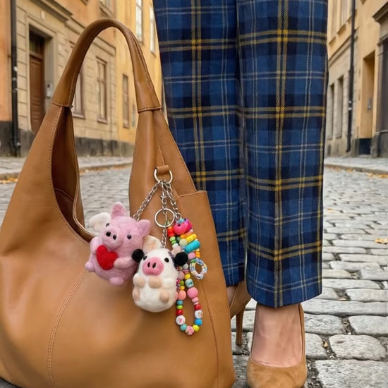 Camel hobo bag with handmade Nepal felt pig and sheep keychains layered with beaded keychain in European street setting