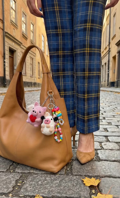 Camel hobo bag with handmade Nepal felt pig and sheep keychains layered with beaded keychain in European street setting