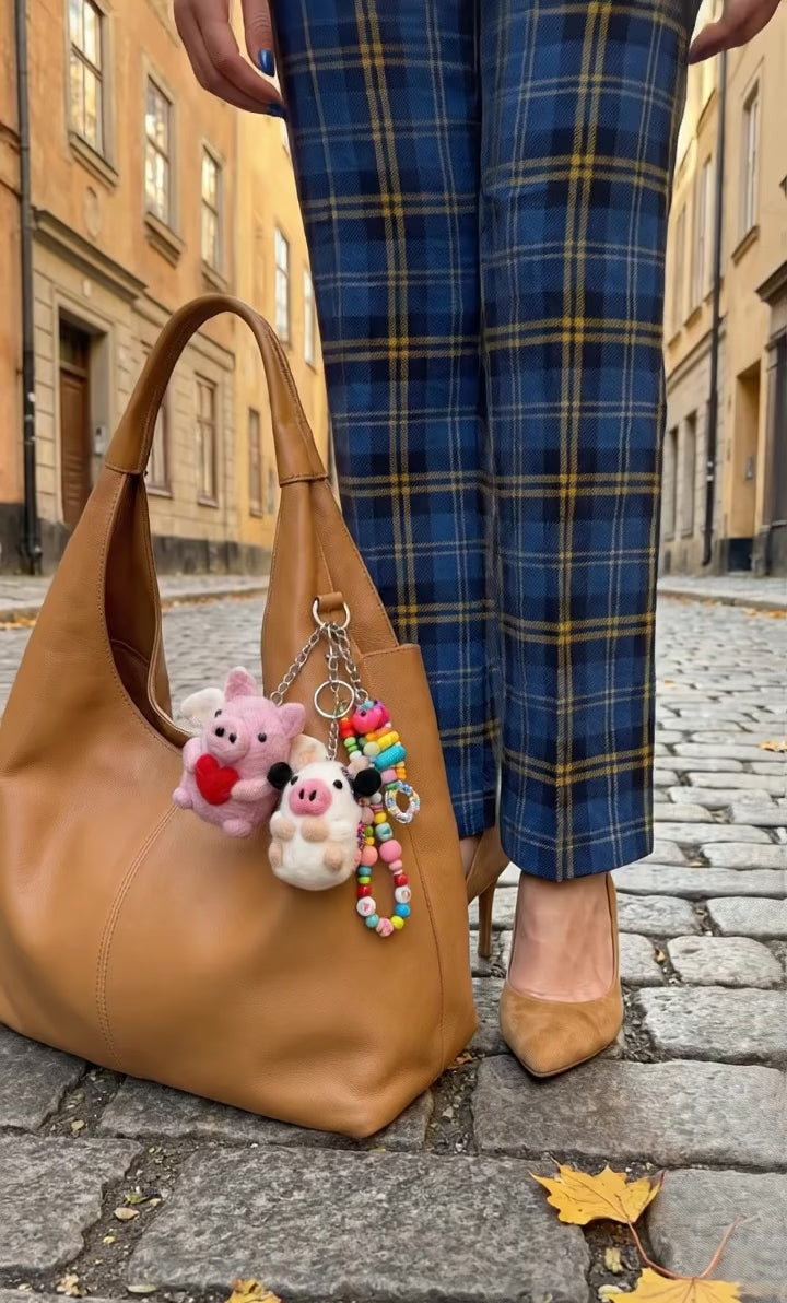 Camel hobo bag with handmade Nepal felt pig and sheep keychains layered with beaded keychain in European street setting