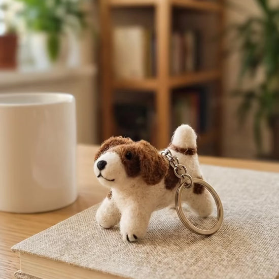 Handmade wool felt spotted dog keychain on wooden desk with coffee mug
