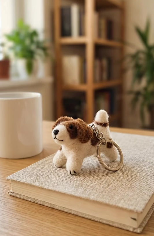 Handmade wool felt spotted dog keychain on wooden desk with coffee mug