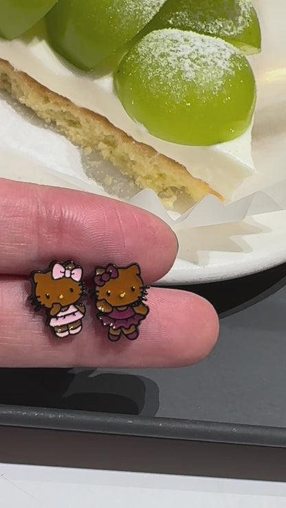 Adorable Hello Kitty–inspired piercing featuring a playful Hawaii-style cat in pink or red dress. Made with hypoallergenic surgical steel. Sold as single.