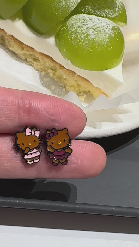 Adorable Hello Kitty–inspired piercing featuring a playful Hawaii-style cat in pink or red dress. Made with hypoallergenic surgical steel. Sold as single.