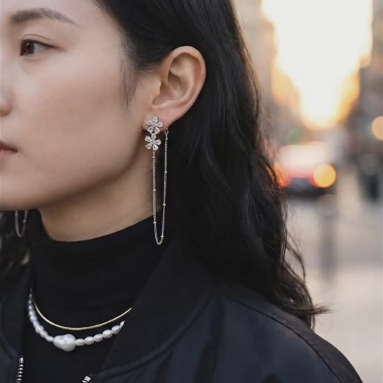 Woman wearing silver floral crystal chain drop earrings with black turtleneck outdoors