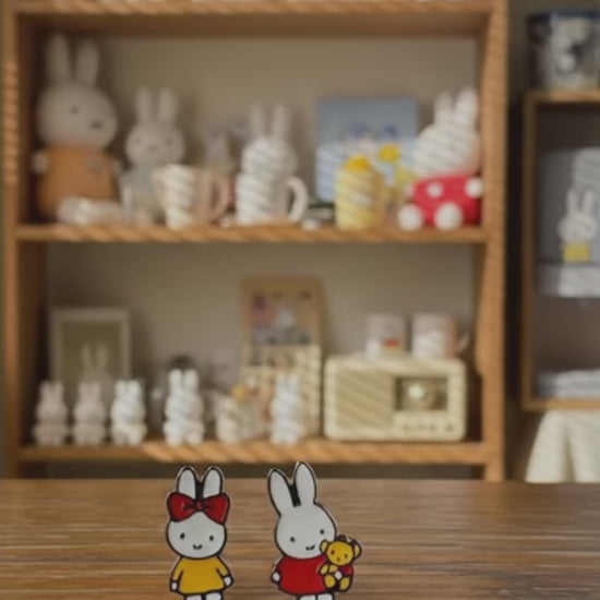 Miffy character earring set displayed on white card with rainy window background, featuring red and yellow enamel studs with 925 sterling silver hypoallergenic posts, Korean handmade kawaii jewelry, cozy lifestyle aesthetic with soft blue pillow and Miffy plush toys